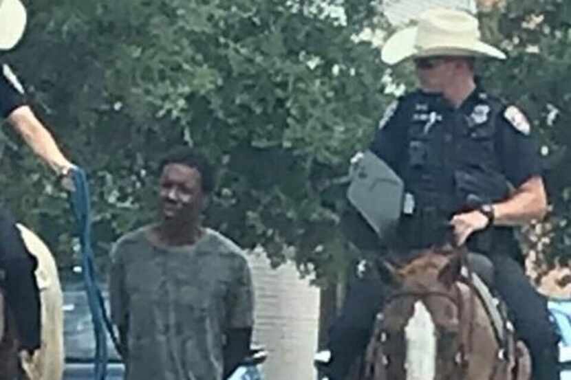 A photo showing a black man being led through Galveston by police officers on horseback has...