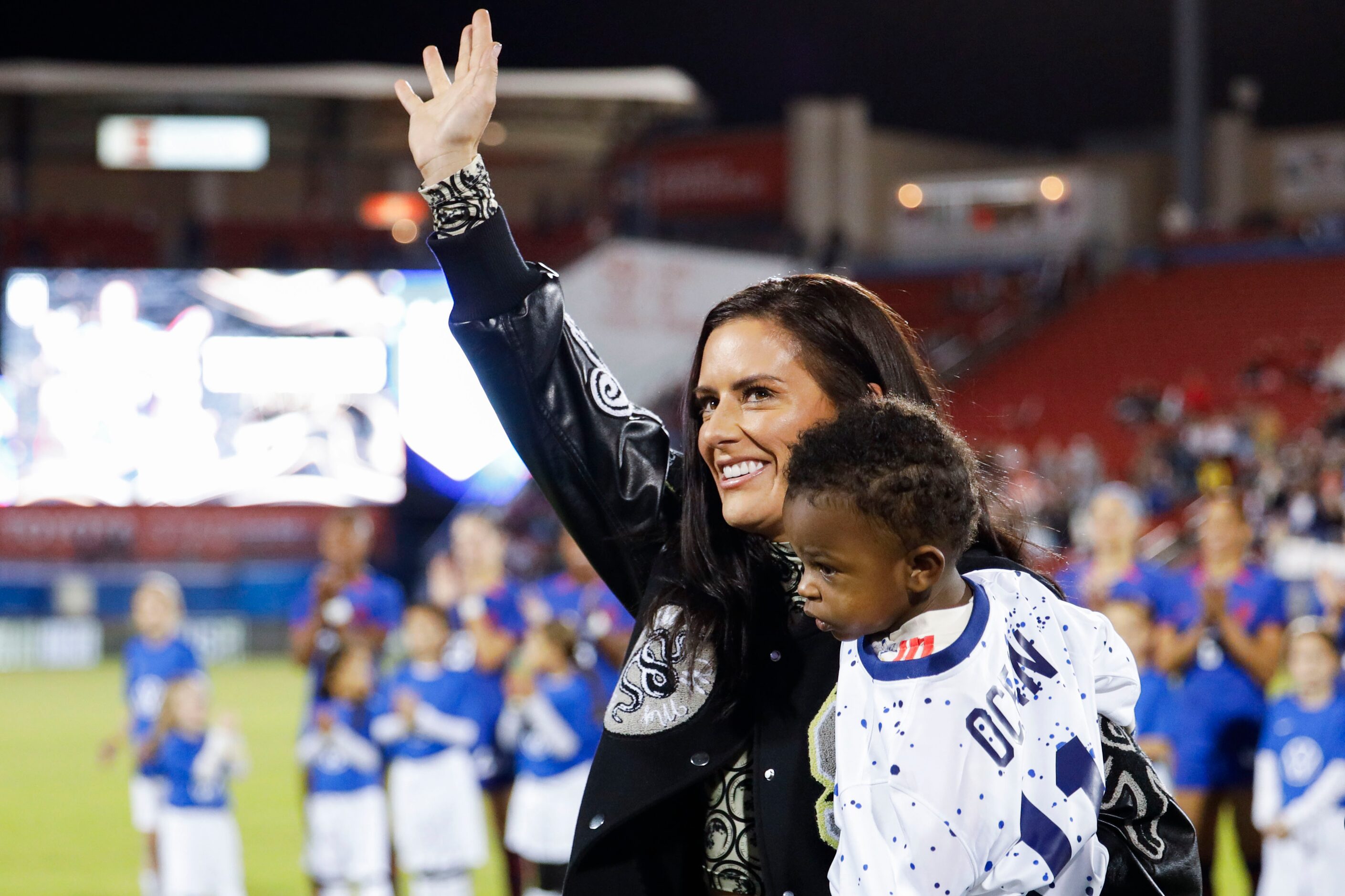 Former United States’ soccer player Ali Krueger waves carrying her son Ocean Maeve...