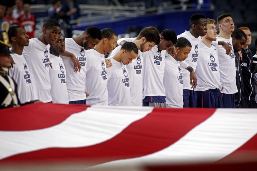 Members of the Connecticut Huskies basketball team stand during the national anthem before...
