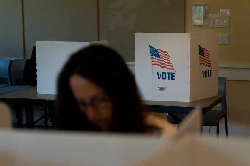 FILE - A voter in the foreground casts her ballots during the Republican primary election in...