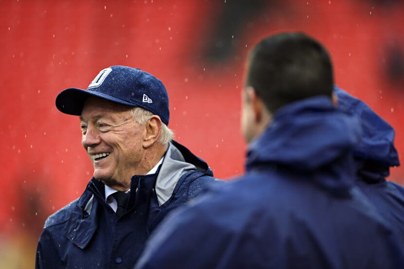 Dallas Cowboys owner Jerry Jones laughs as he talks with others on the field before a game...