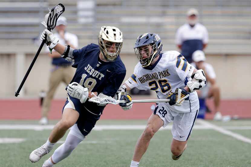 Dallas Jesuit's Caiden Vlasimsky (19) is stick checked by Highland Park's Rhodes Crow (26)...