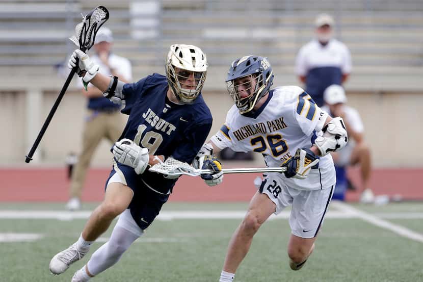 Dallas Jesuit's Caiden Vlasimsky (19) is stick checked by Highland Park's Rhodes Crow (26)...