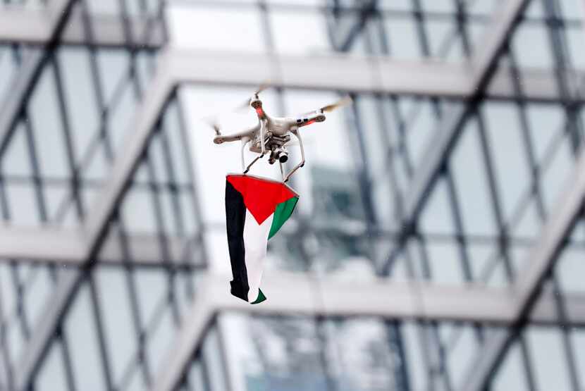 A drone carrying a Palestinian flag hovers over Belo Garden during the rally.