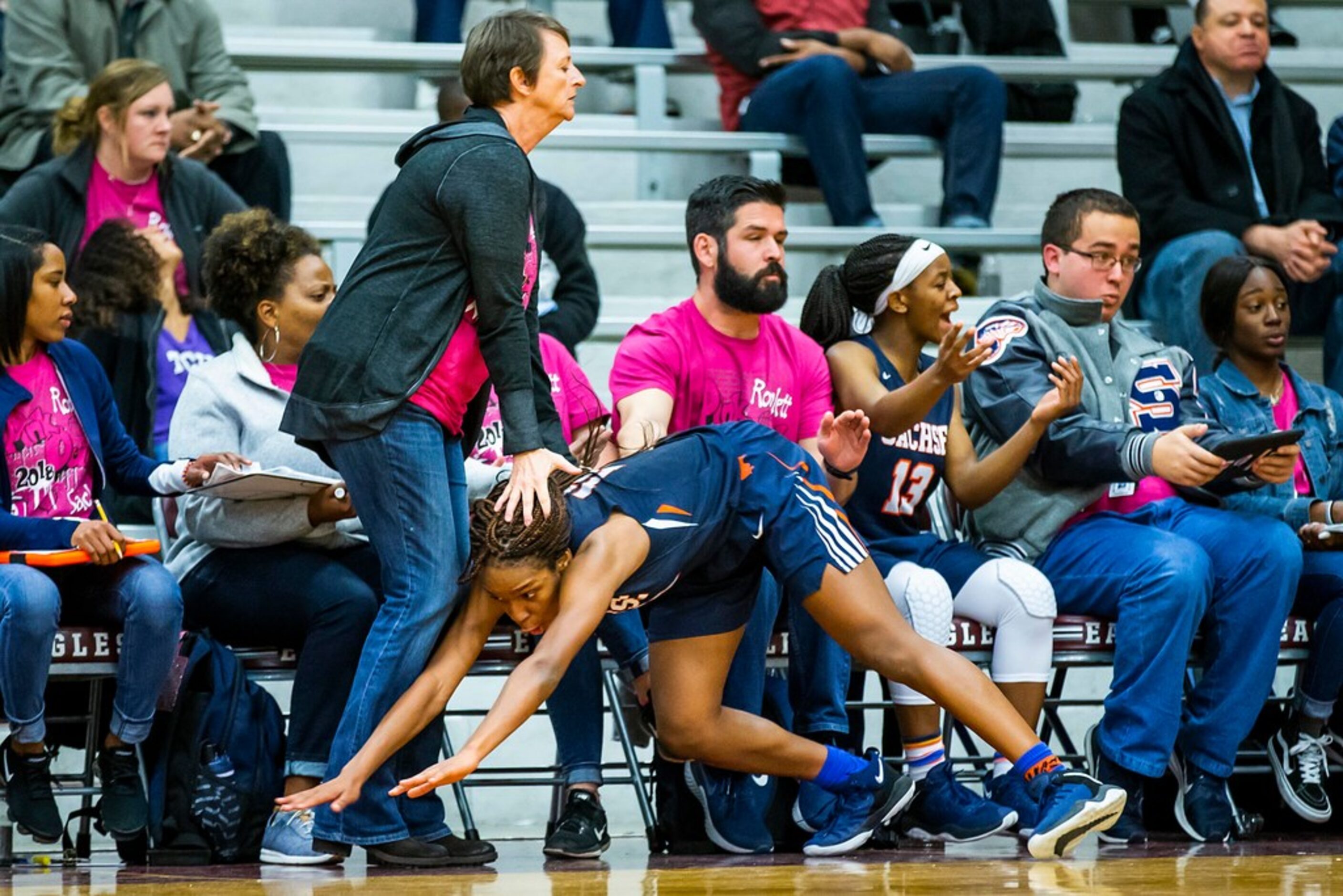 Sachse guard Tia Harvey slides into her team's bench at the feet of head coach Donna...