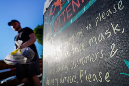 A sign on the sidewalk asks everyone entering Monkey King Noodle Co. in Deep Ellum to wear...