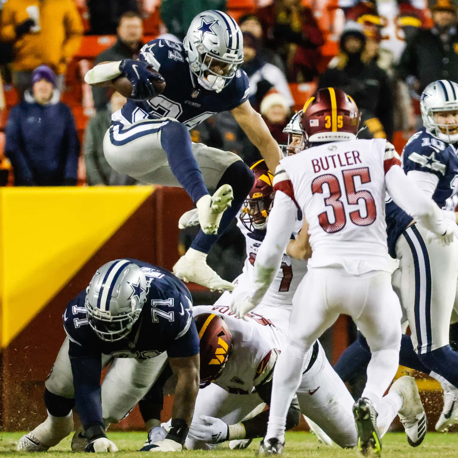 Dallas Cowboys running back Malik Davis (34) jumps over the Washington Commanders defense...
