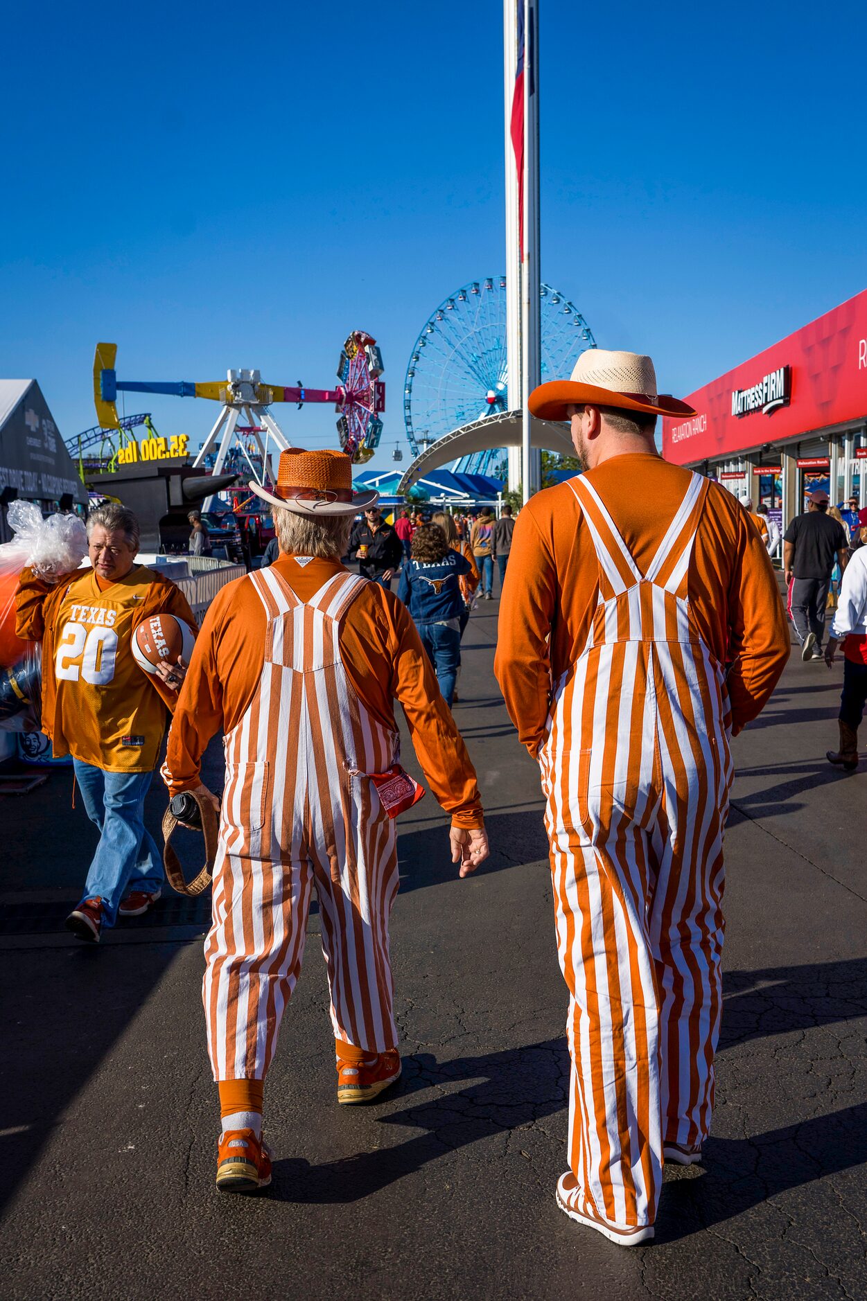 A pair of Texas fans walks toward the midway before an NCAA football game between Texas and...