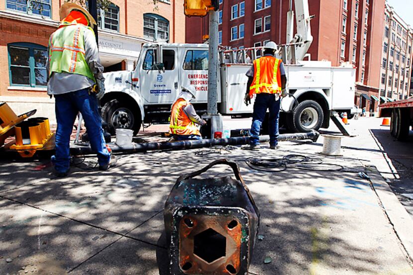 Workers replace a traffic signal outside the Sixth Floor Museum at Dealey Plaza in downtown...