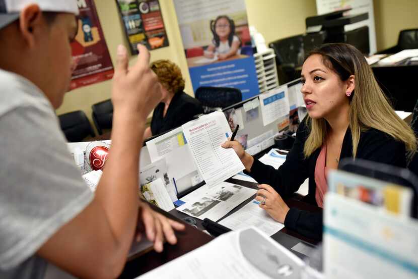 Jasmine Bueno, a financial coach with Catholic Charities, speaks with a Mexican immigrant as...