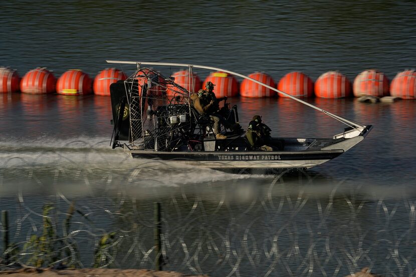 A Texas Highway Patrol boat passes a chain of buoys deployed to help curb illegal crossings...