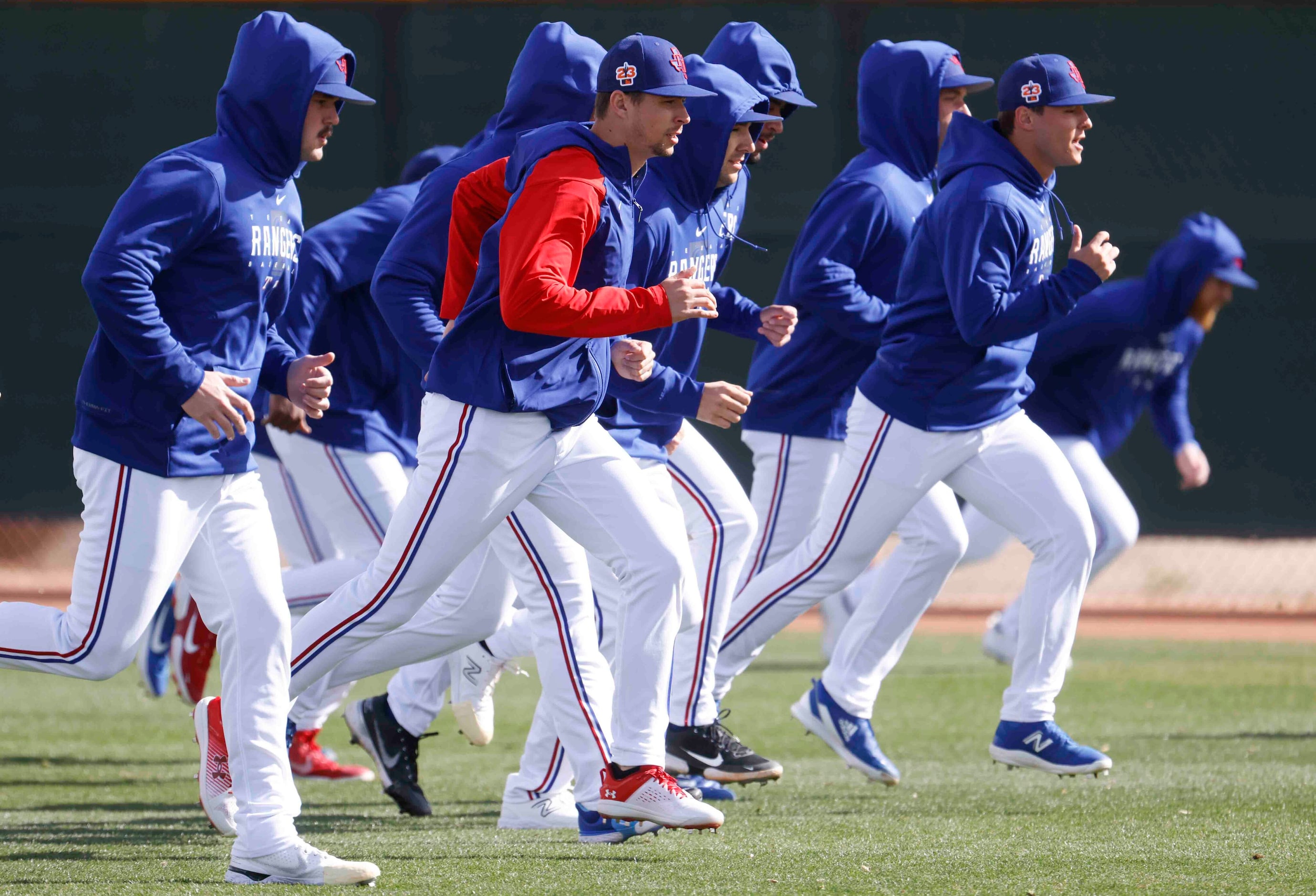 Texas Rangers pitchers Cole Ragans, left, Ricky Vanasco, center, jog with their teammates...