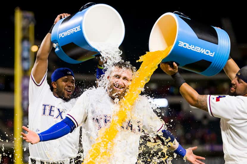 Texas Rangers catcher Jonathan Lucroy is doused with water and sports drink by shortstop...
