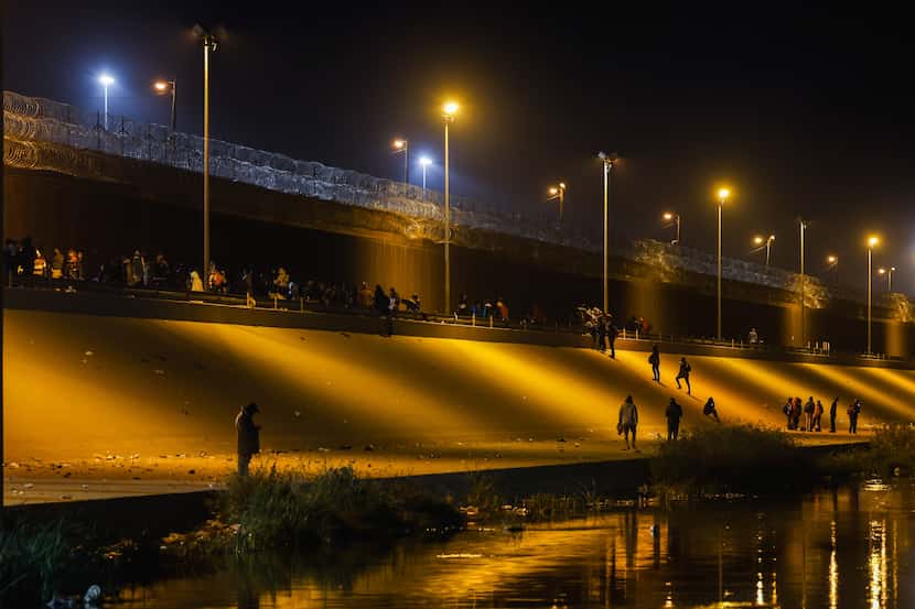 Migrants stand in line at a US-Mexico border gate from the banks of the Rio Grande River in...