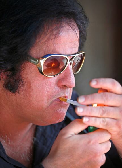 Elvis impersonator Phil Sneed lights a cigarette while performing on North Market Street by...