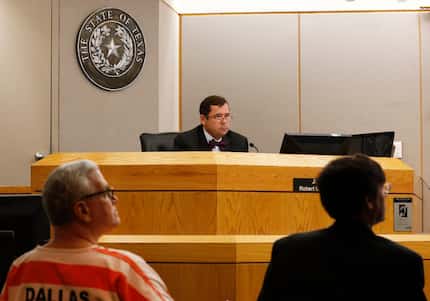 State District Judge Robert Burns, center, listens to testimony during a competency hearing...