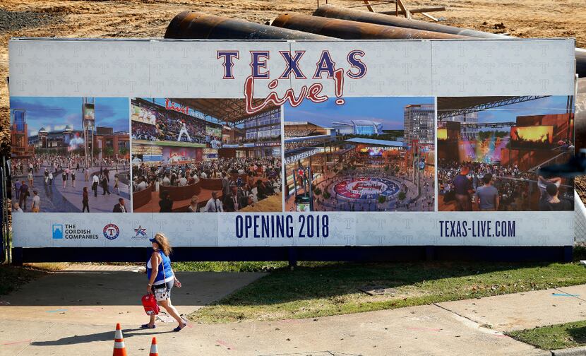 A Texas Rangers fan passes the Texas Live! entertainment complex under construction near...
