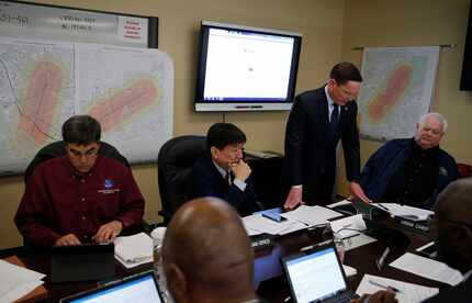Dallas County Judge Clay Jenkins (standing) and others talk on a conference call in the...