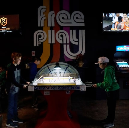 Zackery Verner (9) and Oliver Bench (10) play bubble hockey at Free Play in Arlington.