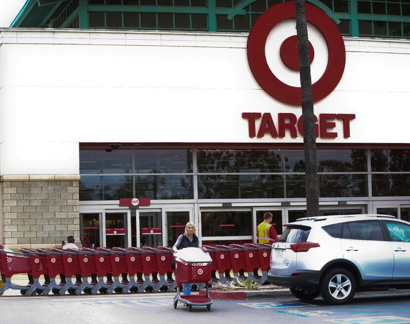 In this Thursday, May 26, 2016, photo, a woman pushes her shopping cart as an employee pulls...