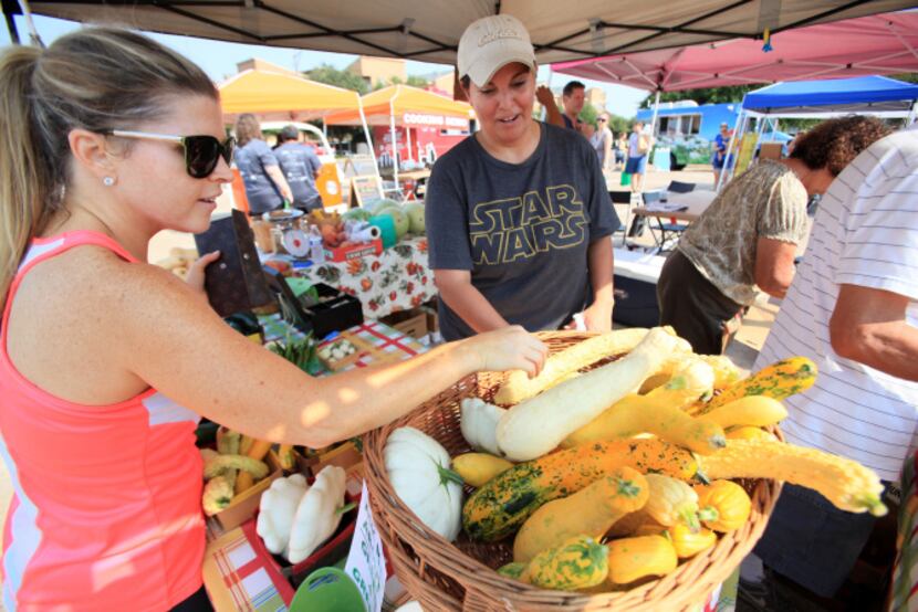 Ashley Dudley, left, purchases squash from Sofia Martinez at the Rae Lili Farm booth, at the...