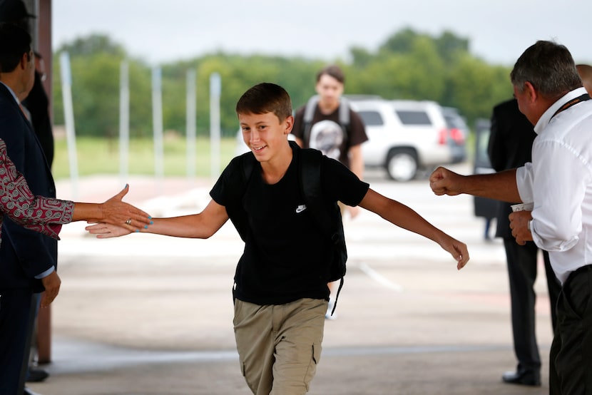 Freshman Wade Nicholson high-fives school and city administrators while walking in on the...