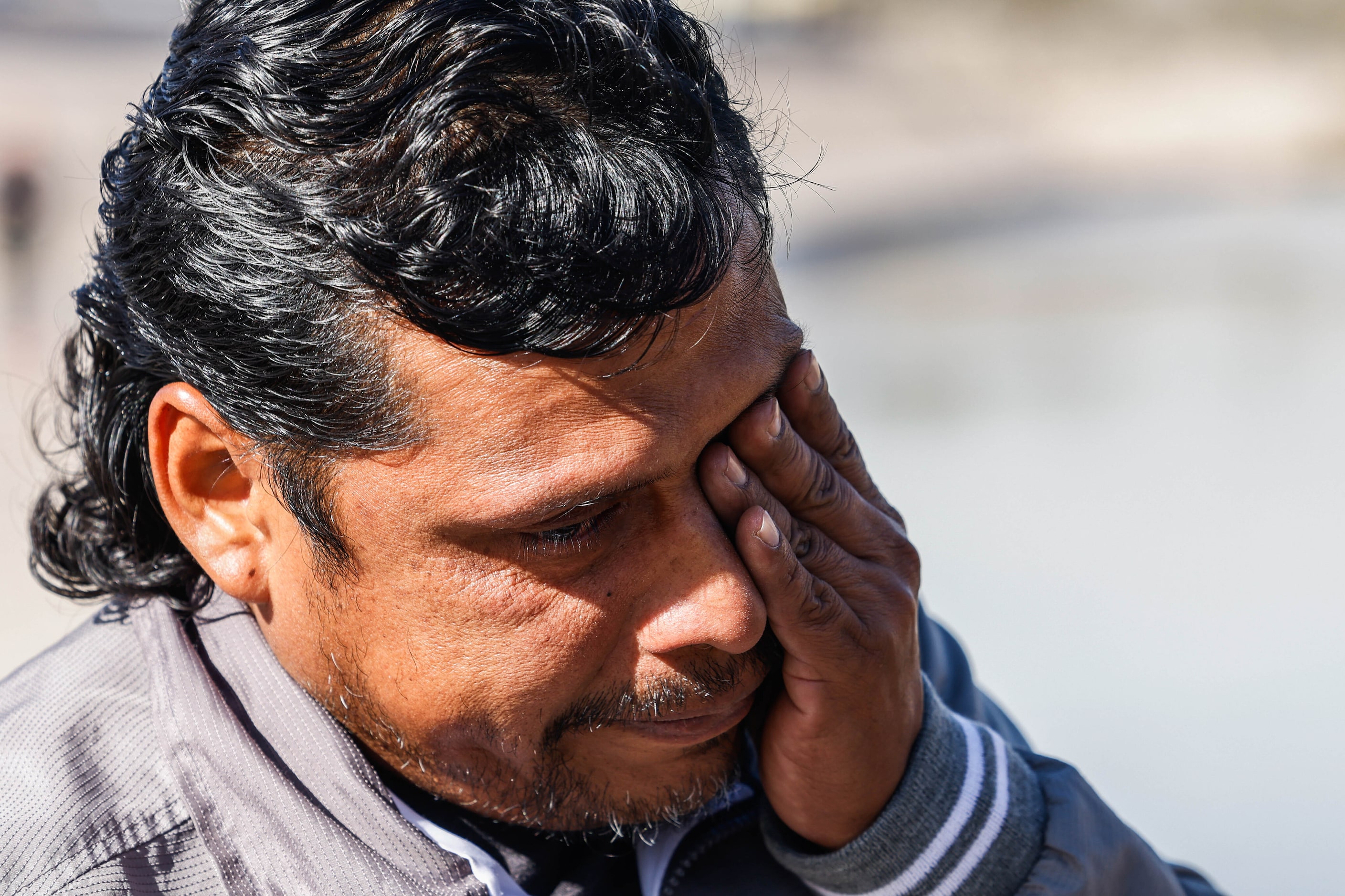 A migrant cries as he sees his wife and child cross the Rio Grande river and into El Paso,...