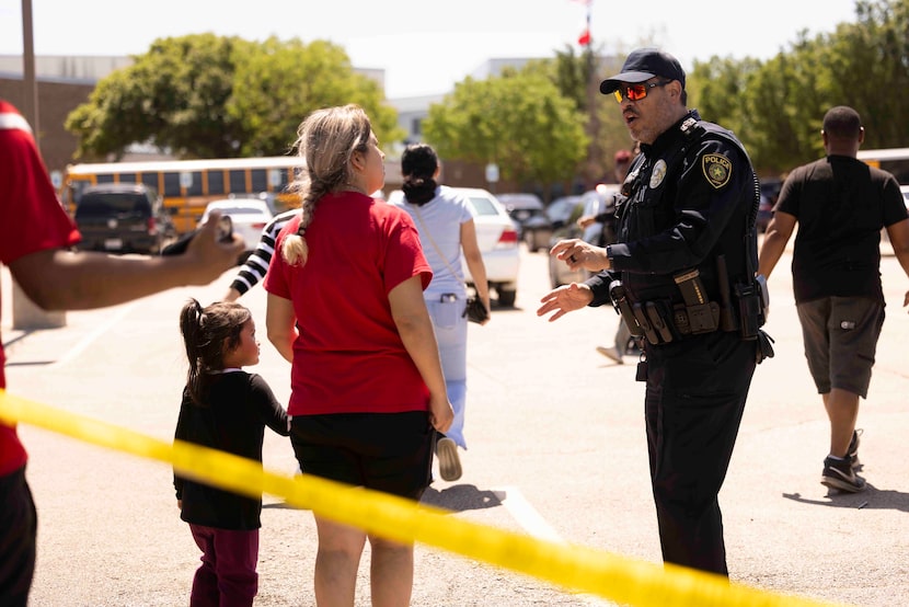 A police officer speaks to a parent after the shooting at Wilmer-Hutchins High School in...