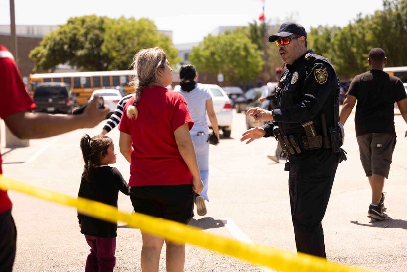 A police officer speaks to a parent after the shooting at Wilmer-Hutchins High School in...