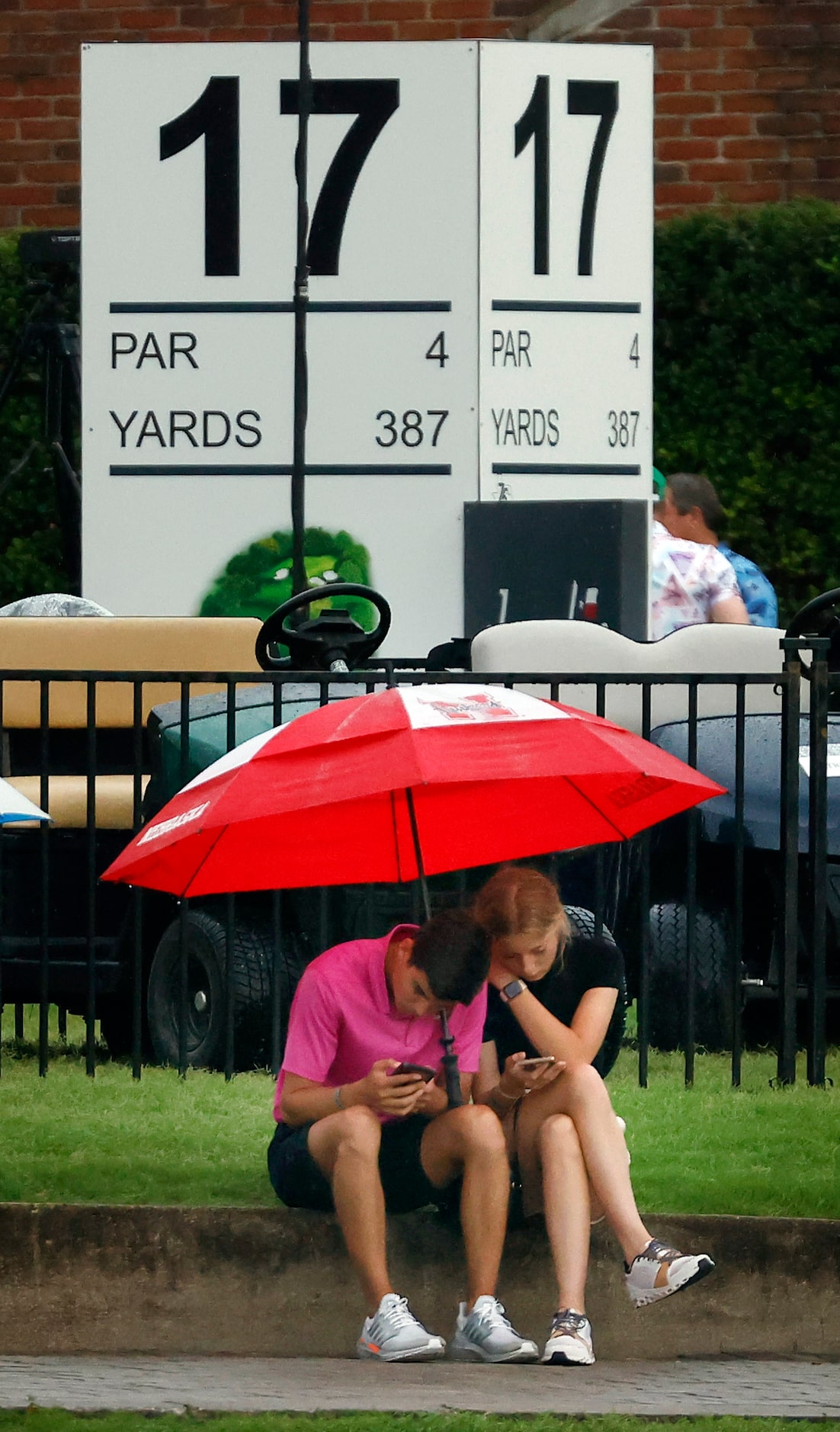 A pie of kids find shelter under and umbrella near the 17th tee box after golf play was...