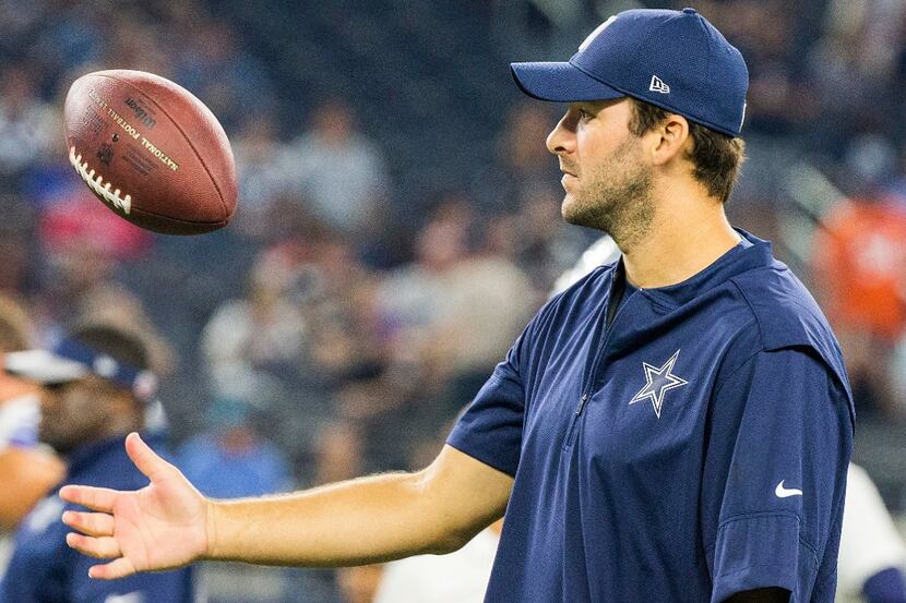 Dallas Cowboys quarterback Tony Romo tosses a football as the teams warm up before an NFL...
