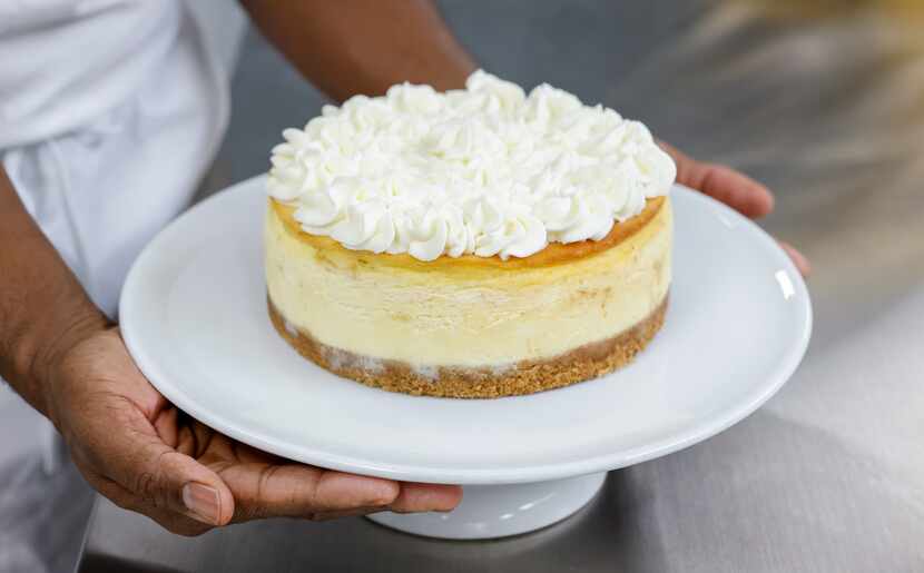 Owner Valery Jean-Bart held a classic cheesecake he decorated with fresh whipped cream in...