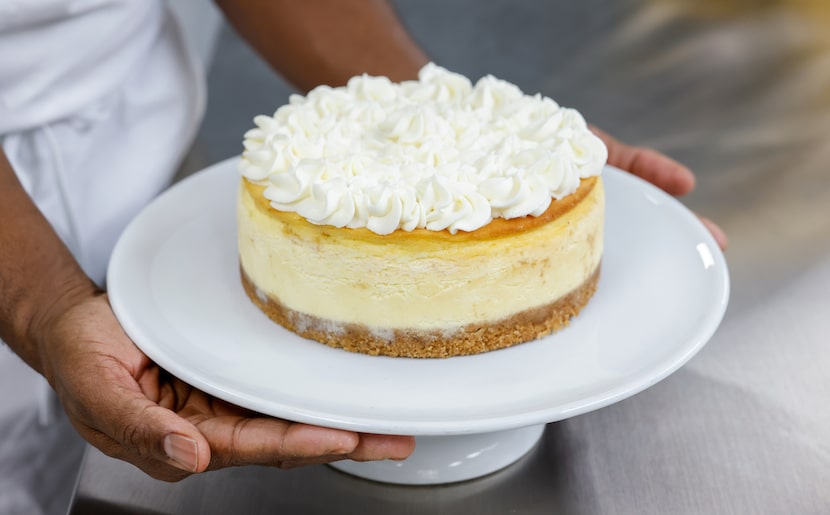 Owner Valery Jean-Bart held a classic cheesecake he decorated with fresh whipped cream in...