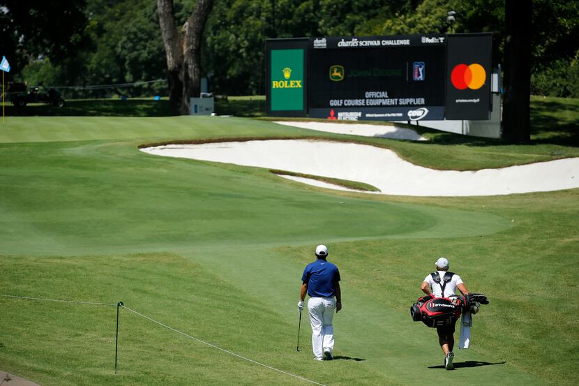 Golfer Patrick Reed and his caddie walk alone up the par-3 No. 8 during a Charles Schwab...