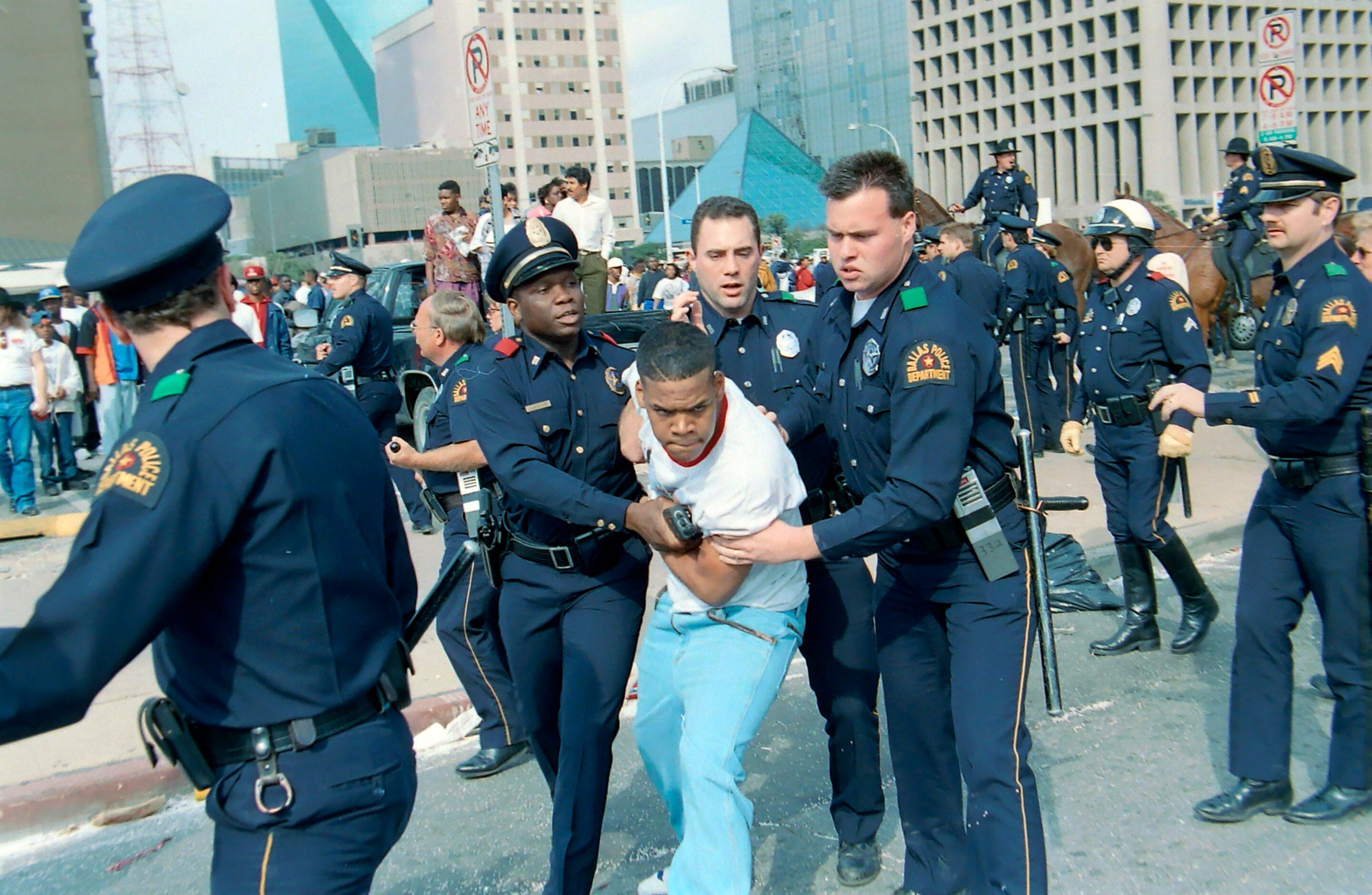 Dallas Police officers detain a teenager after violence erupted along Commerce St following...