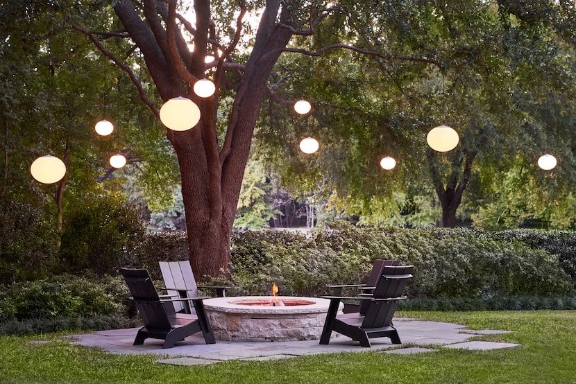 Artful globe pendants hang from the limbs of a live oak. “They  look like they’re suspended...