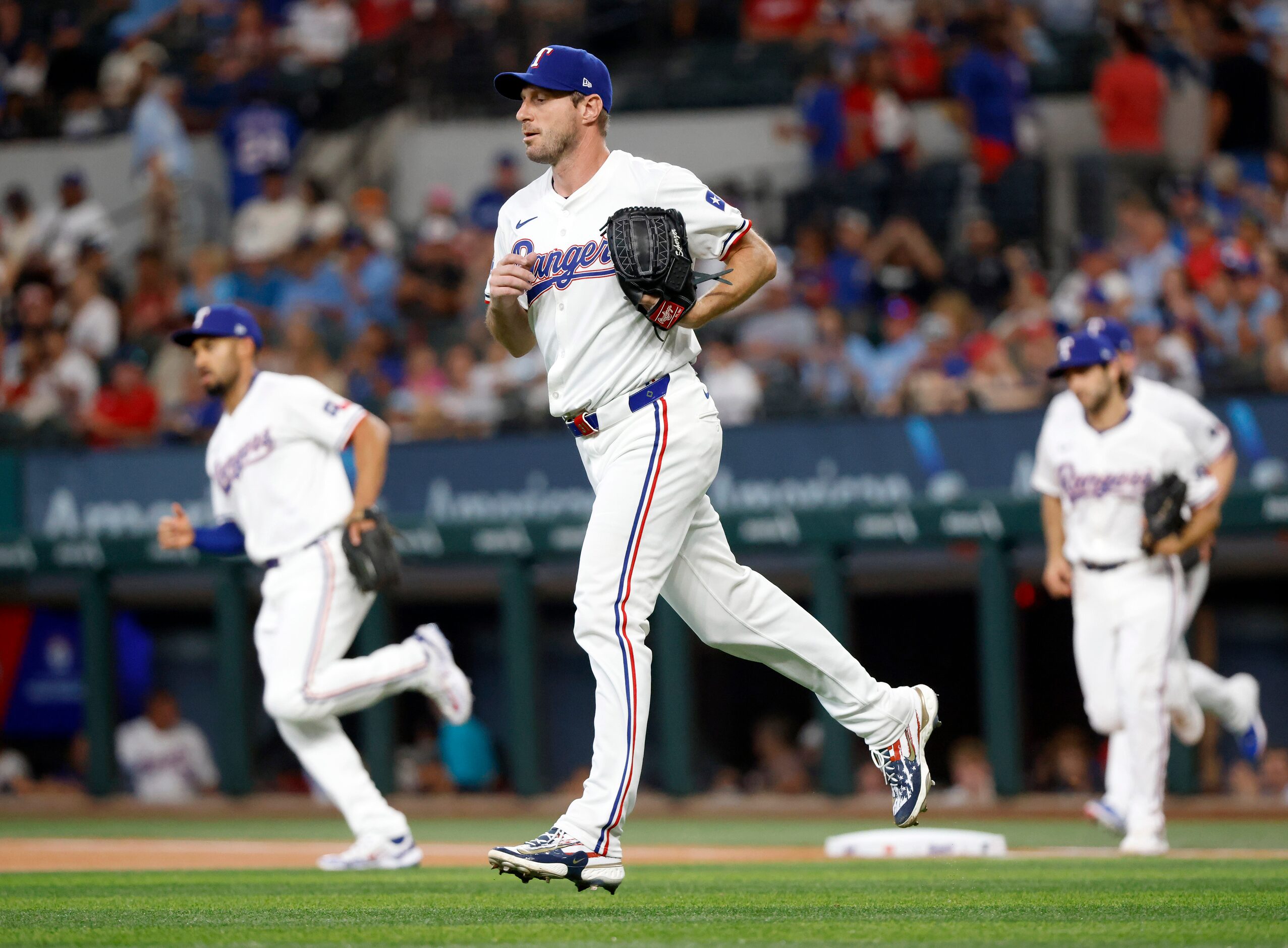 Texas Rangers pitching coach Mike Maddux (center) and his teammates take the field to face...