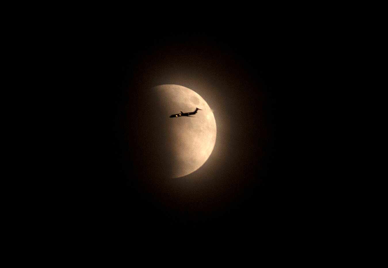 An airplane passes in front of the moon during the lunar eclipse on Sept. 27, 2015, in  Fort...