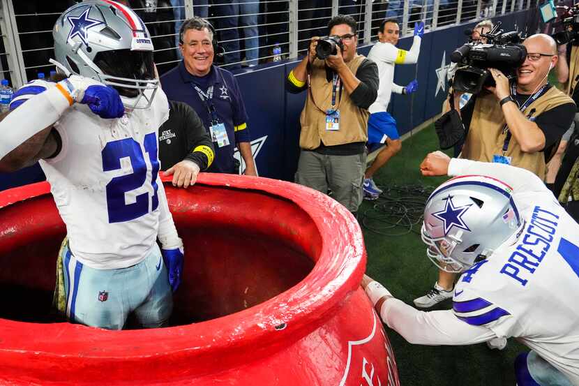 Dallas Cowboys running back Ezekiel Elliott (21) pops out of a Salvation Army kettle as...