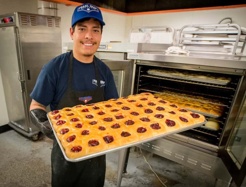 Luis Castillo pulls a fresh batch of kolaches from the oven at Pearl Snap Kolaches in Fort...