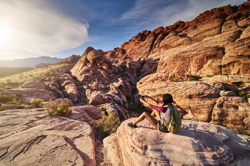 Foto de mujer tomando fotos con su teléfono en una montaña.