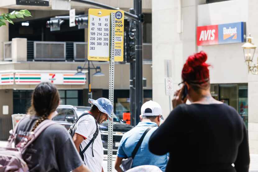 People wait for their bus at a bus stop on Commerce St in Dallas on Thursday, June 23. 2022.