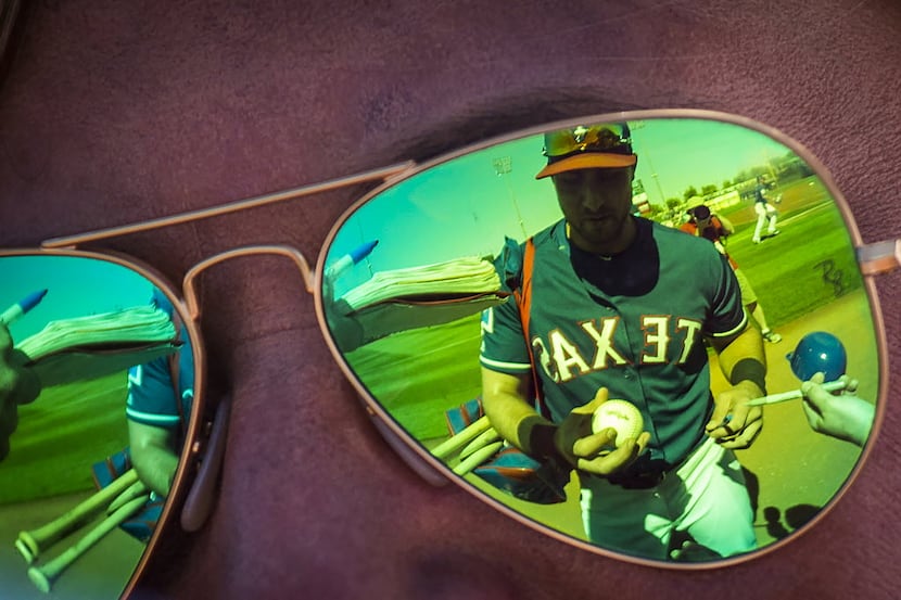 Texas Rangers third baseman Joey Gallo is reflected in a fan's sunglasses as he signs...