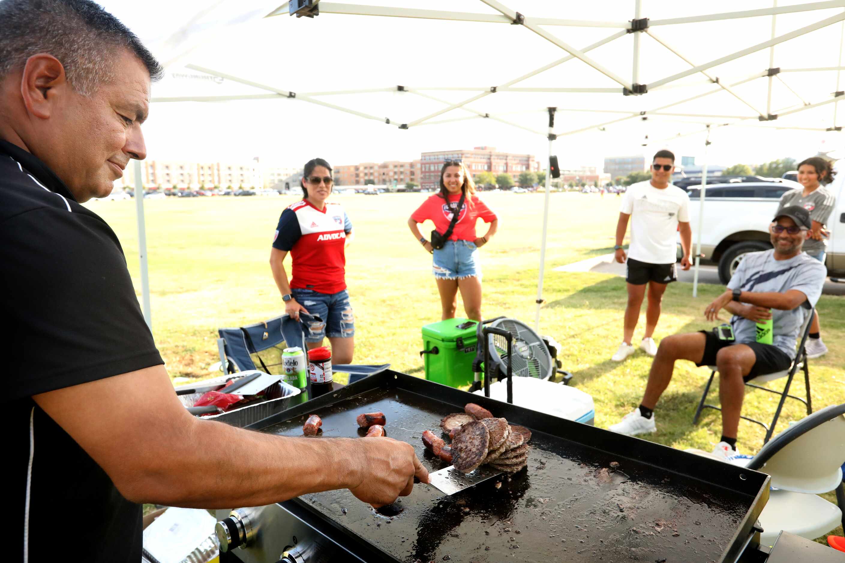 Tony Falcon, left, grills some burgers as he waits for the gates to open for an FC Dallas...