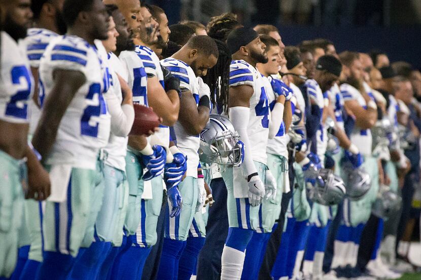Dallas Cowboys players stand for the national anthem before an NFL football game against the...
