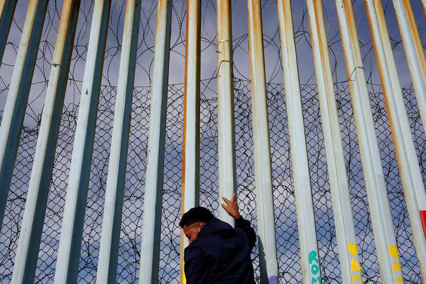 A man holds on to the border wall along the beach on Jan. 8, 2019, in Tijuana, Mexico. Ready...