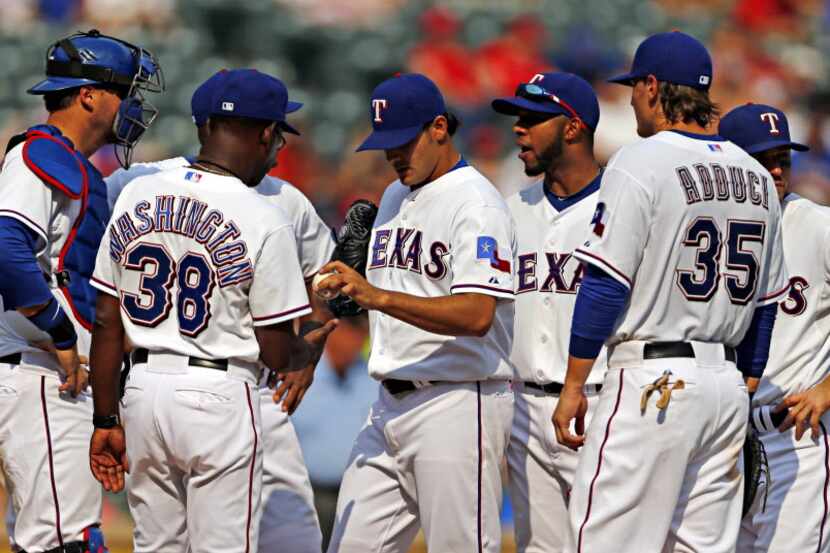 Texas Rangers manager Ron Washington (38) retires starting pitcher Martin Perez (center)...