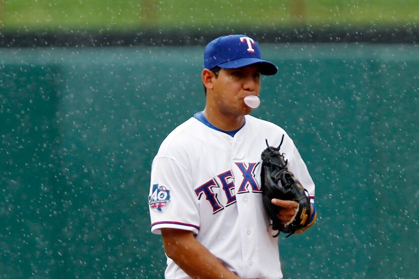 Texas Rangers shortstop Luis Hernandez (3) blows a bubble in the rain during the second...