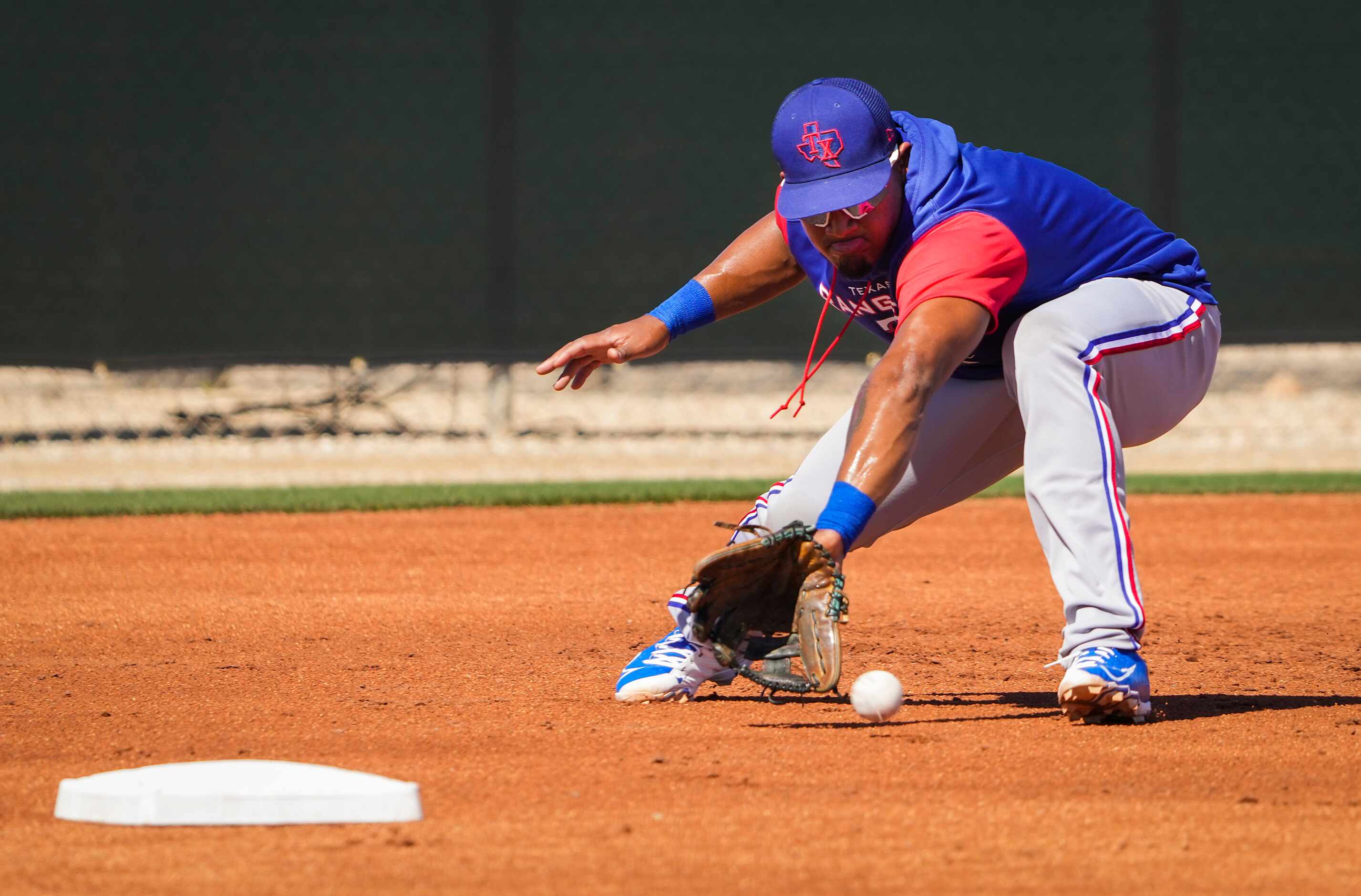 Texas Rangers infielder Andy Ibáñez fields grounders at third base in a defensive drill...