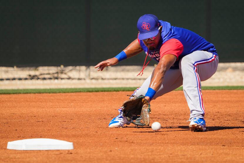 Texas Rangers infielder Andy Ibáñez fields grounders at third base in a defensive drill...